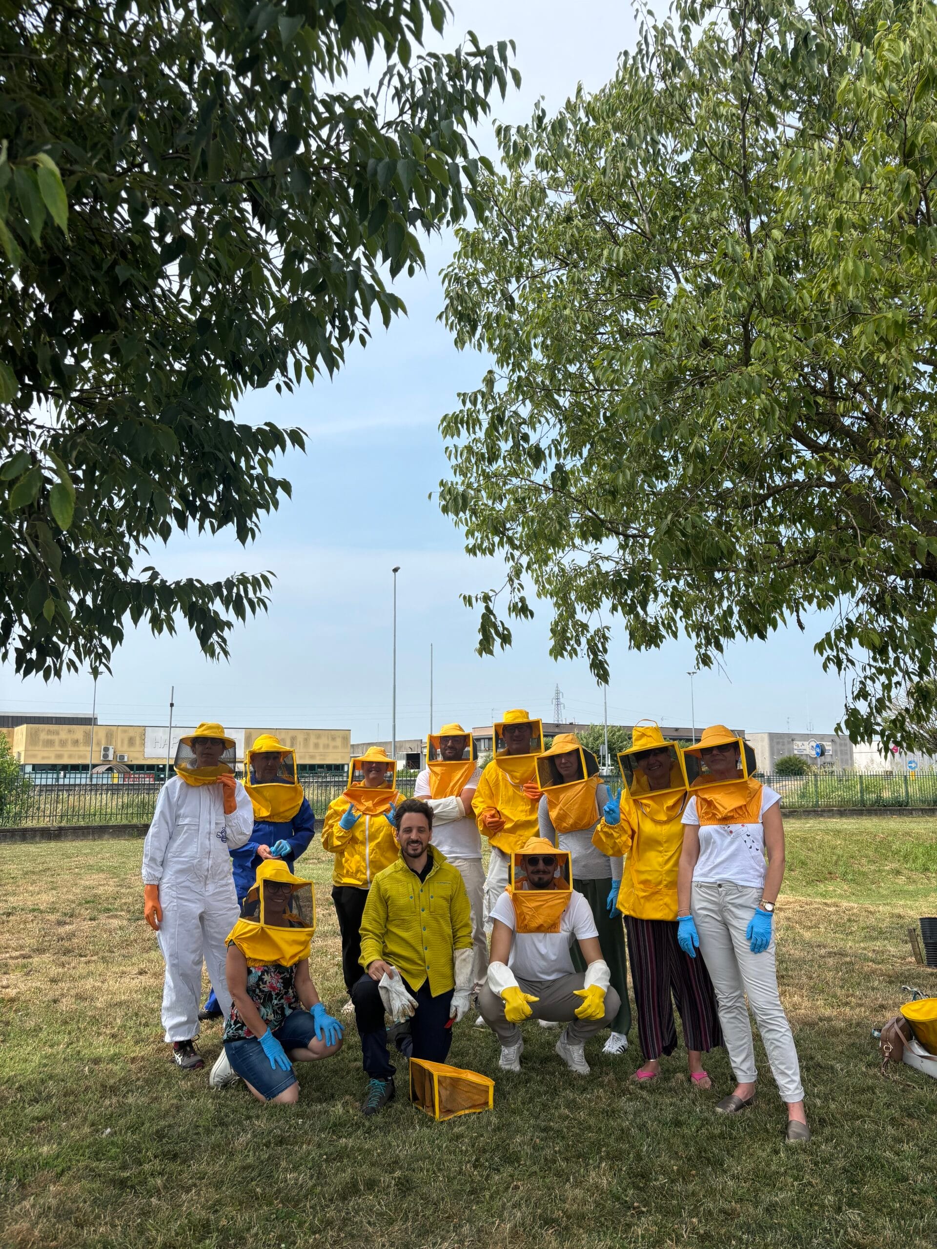 Dipendenti con tute e cappelli da apicoltore durante un'esperienza di team building